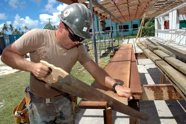 builder cutting a plank with a hand saw